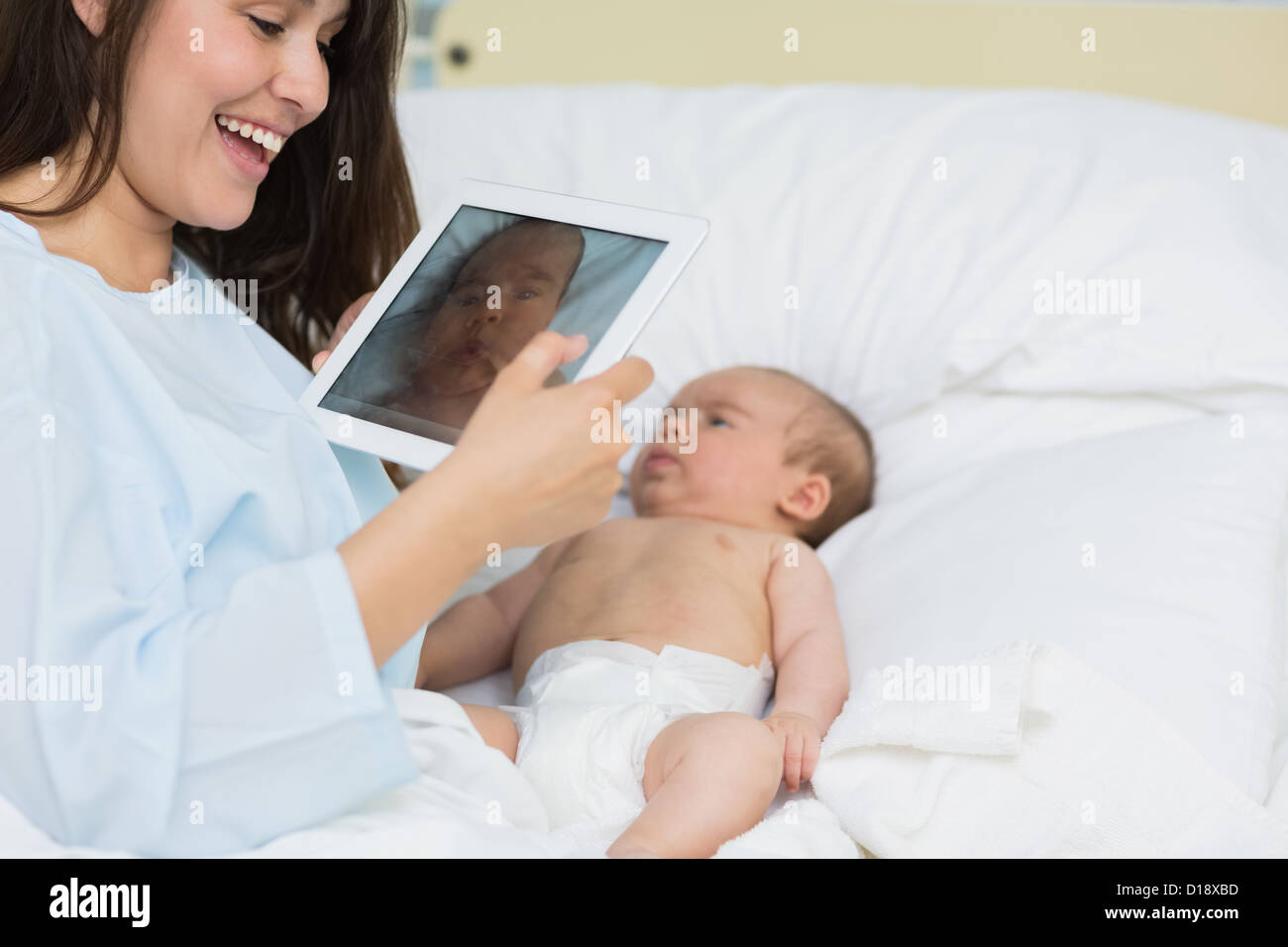 Mutter mit einem Tablet um ein neugeborenes Baby fotografieren Stockfoto