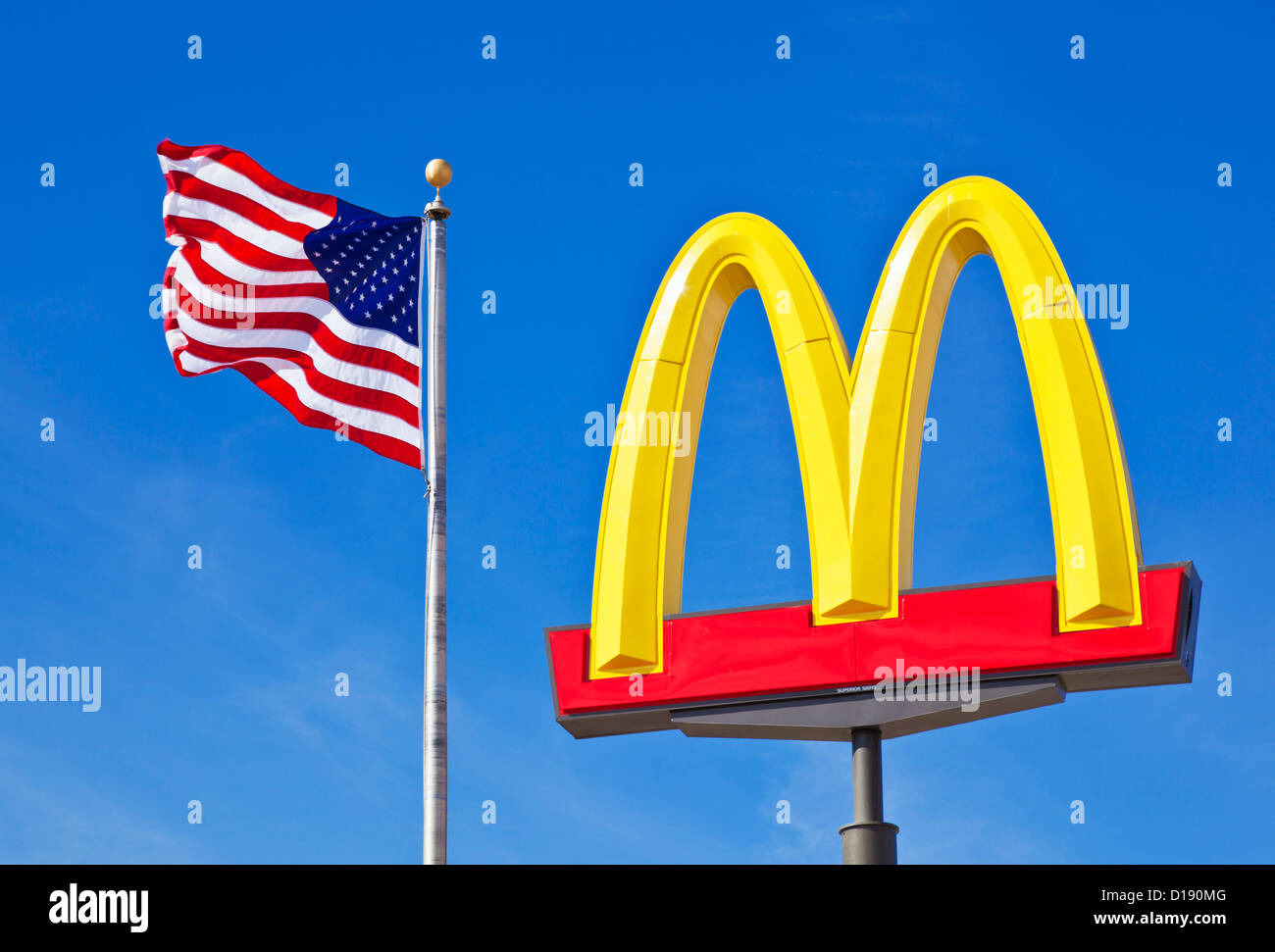 McDonald's-Logo Bögen Zeichen gegen ein klarer blauer Himmel mit einer amerikanischen Flagge Stars und stripes USA Vereinigte Staaten von Amerika Stockfoto
