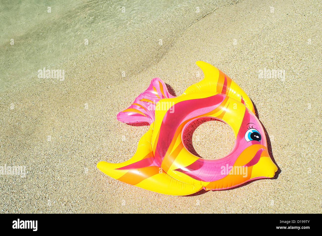 Aufblasbare Fische Ring In Pink, gelb und Orange, auf Sand zu legen. Stockfoto