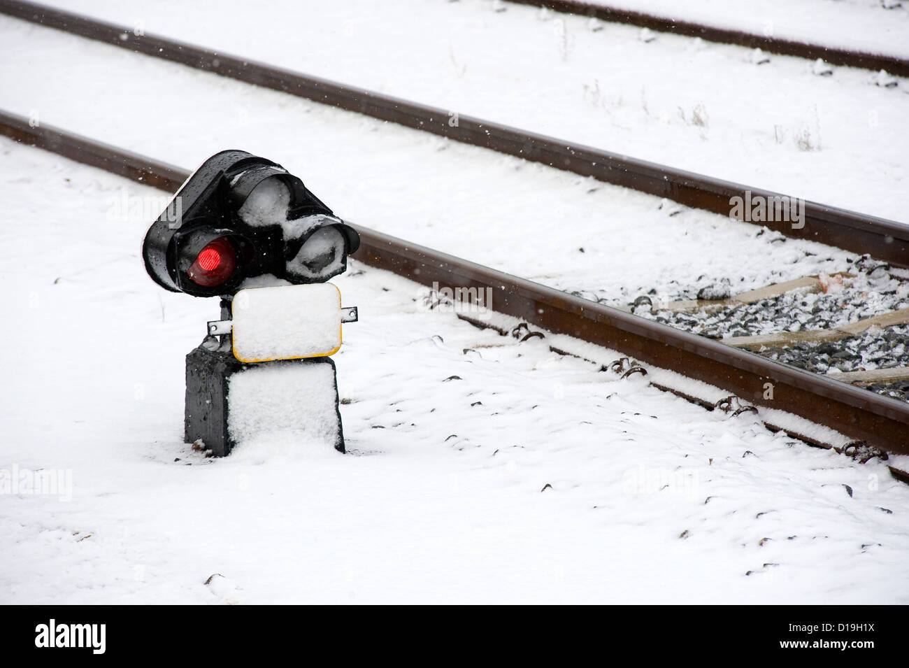 Eine rote Ampel-Signal in der Nähe ein Bahngleis mit Schnee bedeckt Stockfoto