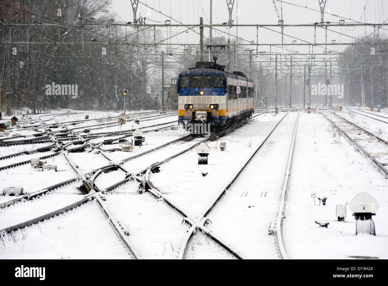 Ein Zug ist im Winter auf tief verschneiten Bahnhof ankommen. Stockfoto