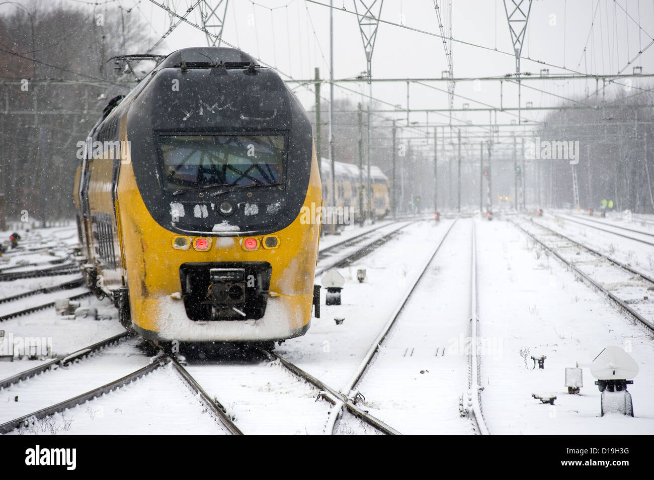 Ein Zug ist im Winter auf tief verschneiten Bahnhof ankommen. Stockfoto