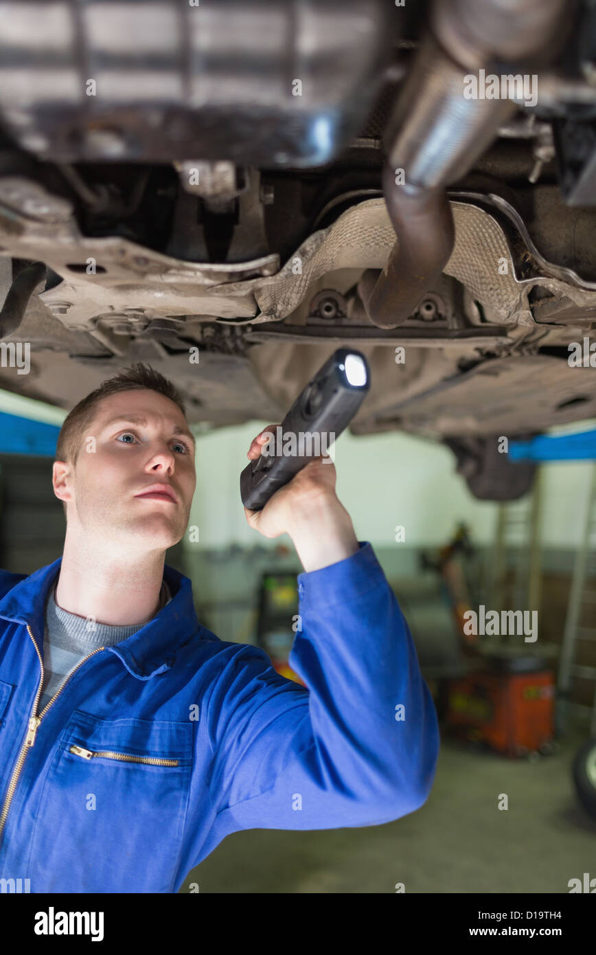 Mechaniker mit Taschenlampe prüfen unter Auto Stockfoto