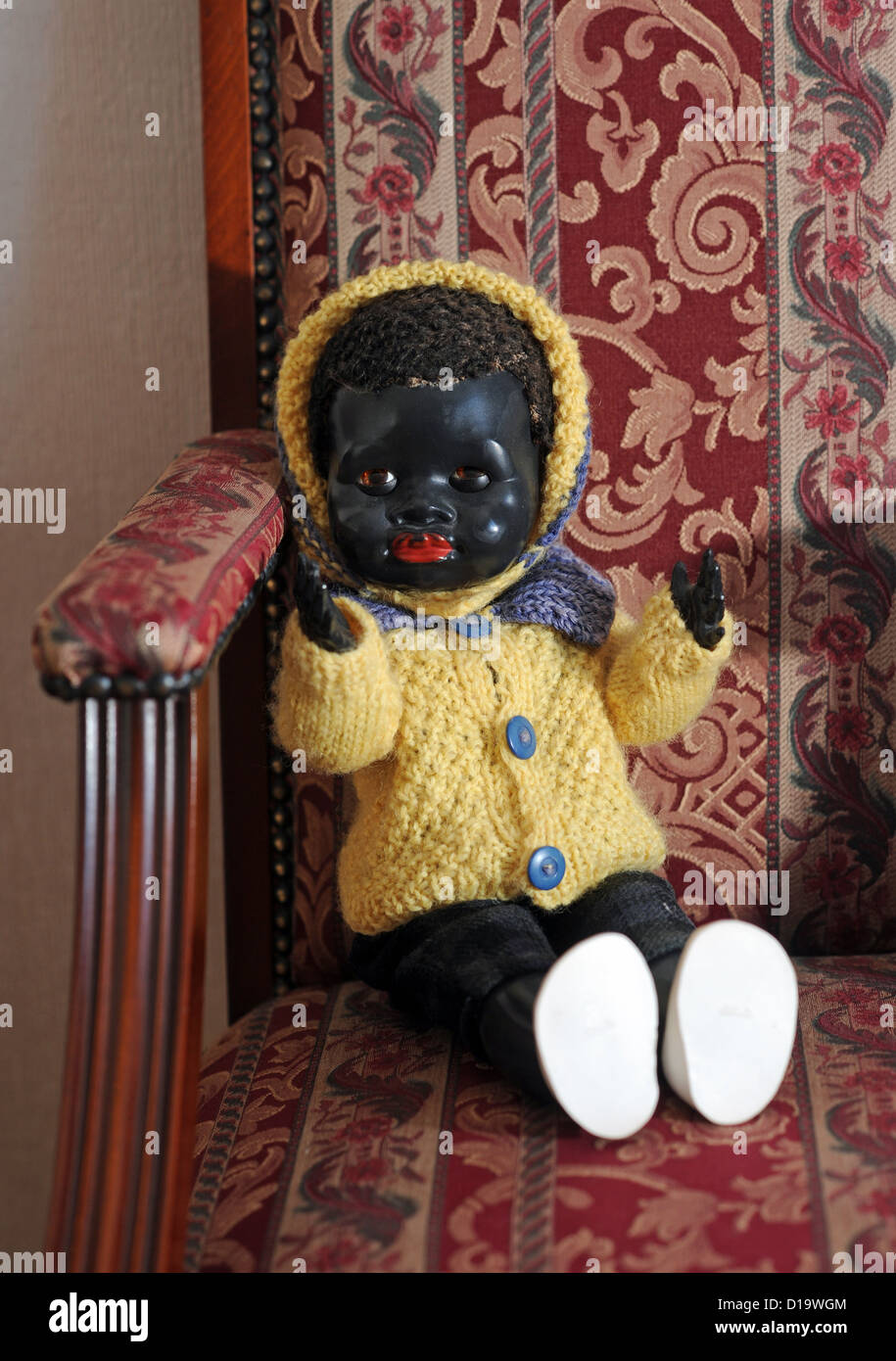 Antikes schwarzes Baby China Spielzeugpuppe in einem Stuhl Stockfoto