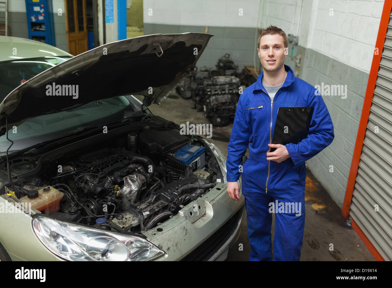 Mechaniker stehend mit dem Auto mit offener Haube Stockfoto