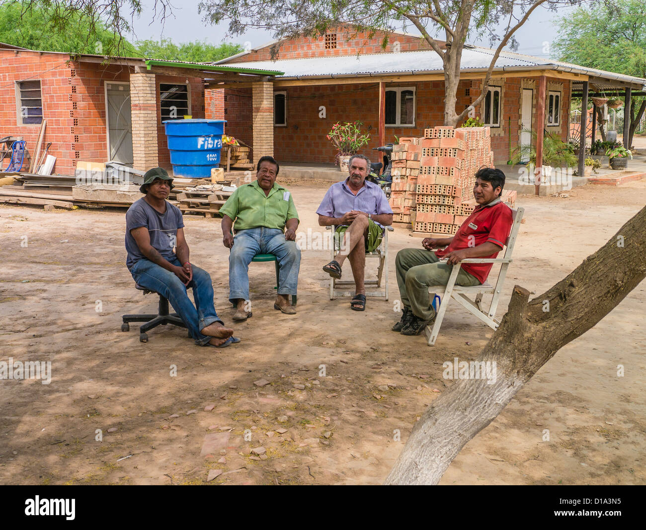 Vier paraguayischen Männer sitzen auf Stühlen außerhalb in der Chaco-Region von Paraguay sprechen. Stockfoto