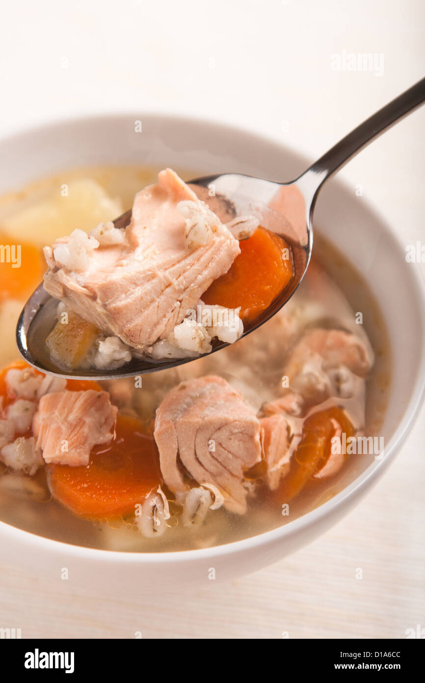Fischsuppe mit Lachs und Orge Perlé in Löffel auf Schüssel Stockfoto
