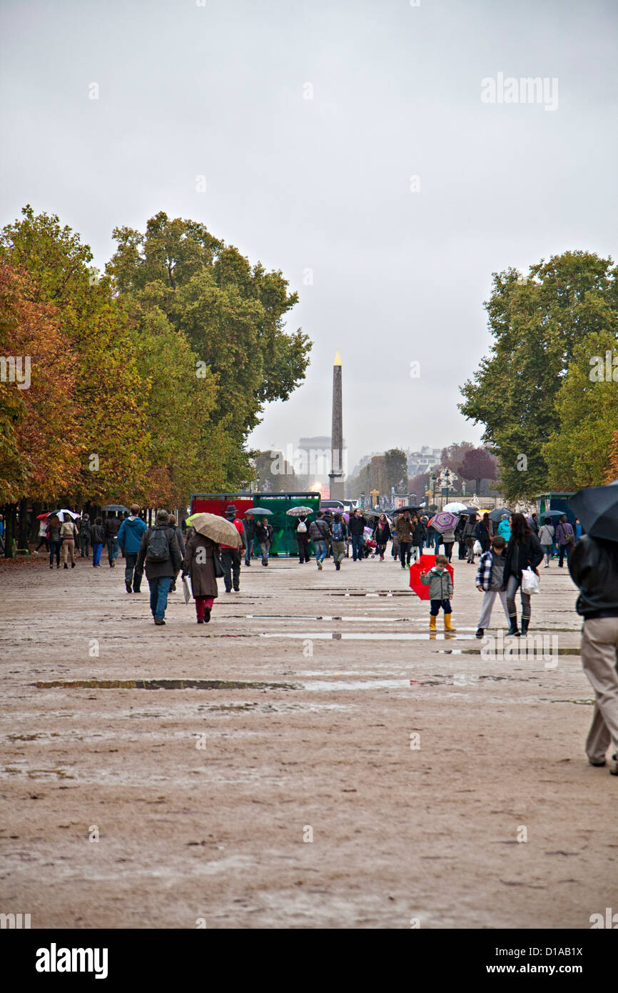 Menschen, die in den Gärten des „Jardin des Tuileries“ in der Nähe des Louver, Paris, mit Sonnenschirmen und Pfützen, Herbstwetter in Paris spazieren gehen Stockfoto