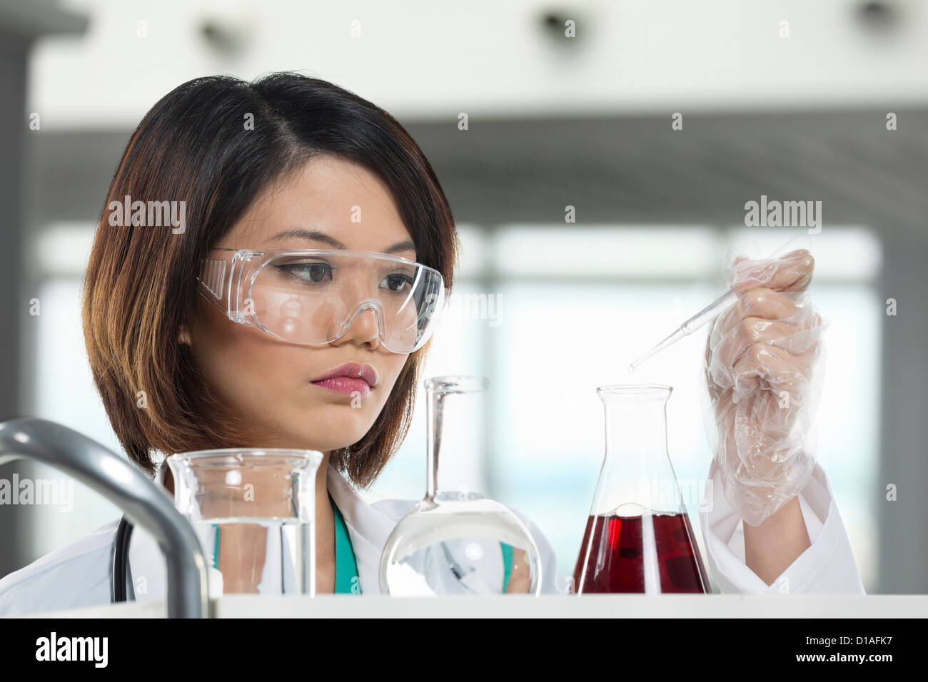 Eine chinesische wissenschaftlicher Mitarbeiter an einer flüssigen Lösung in einem Labor. Wissenschaftlerin Analyse eine Lösung. Stockfoto