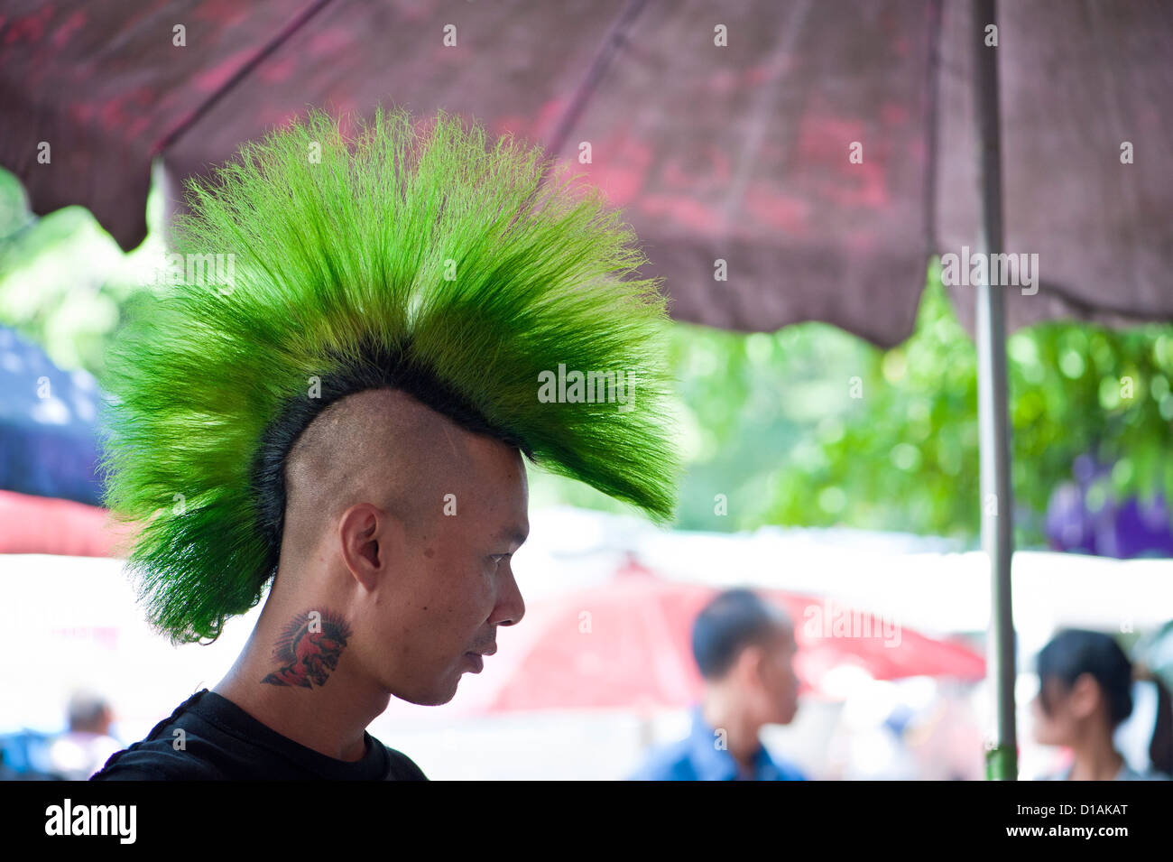 Thai Mann mit grünen Haaren und eine Tätowierung auf dem Sonntagsmarkt Stockfoto