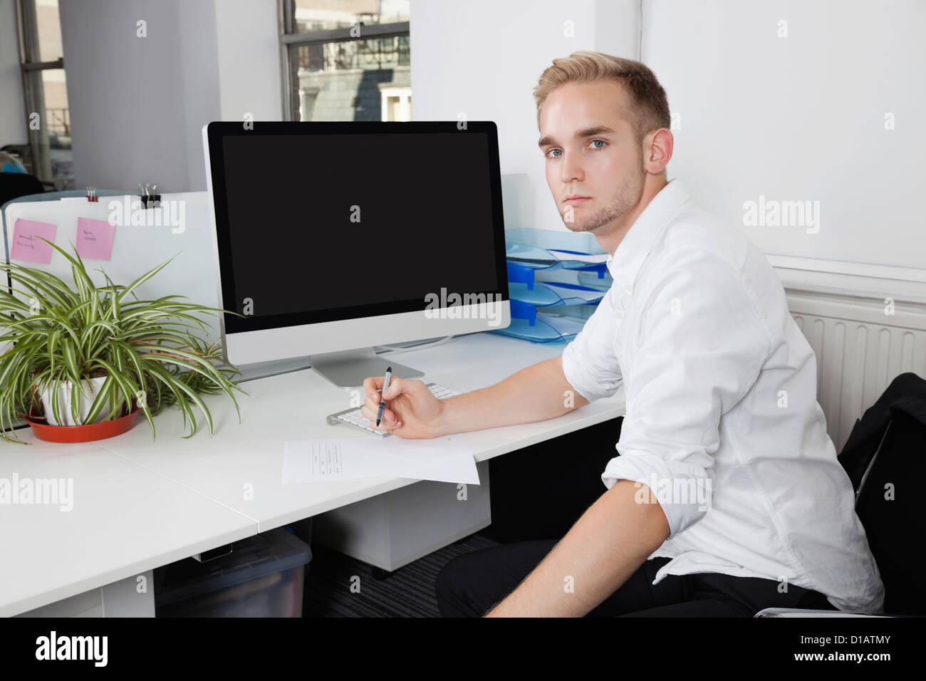 Porträt junger Geschäftsmann Schreiben von Notizen auf Papier am Schreibtisch Stockfoto