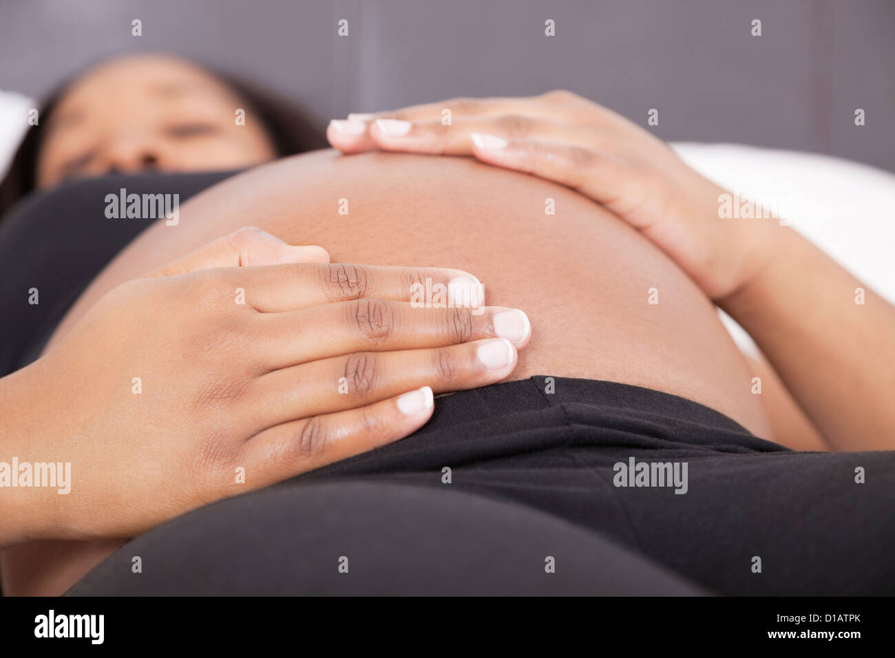Junge schwangere Frau entspannende Hände auf Bauch Stockfoto
