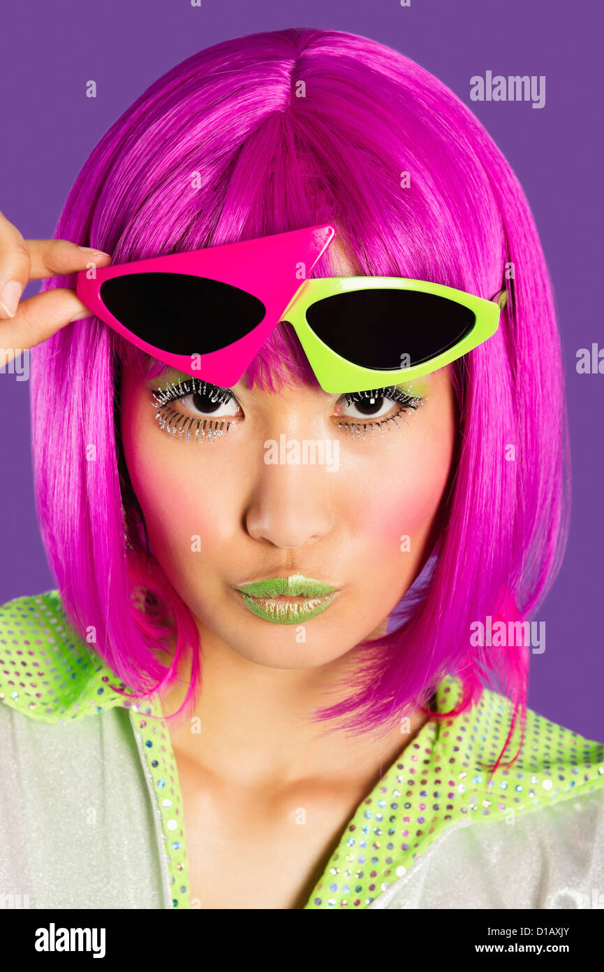 Funky Mädchen Porträt in rosa Perücke Fältelungen Lippen über lila Hintergrund Stockfoto