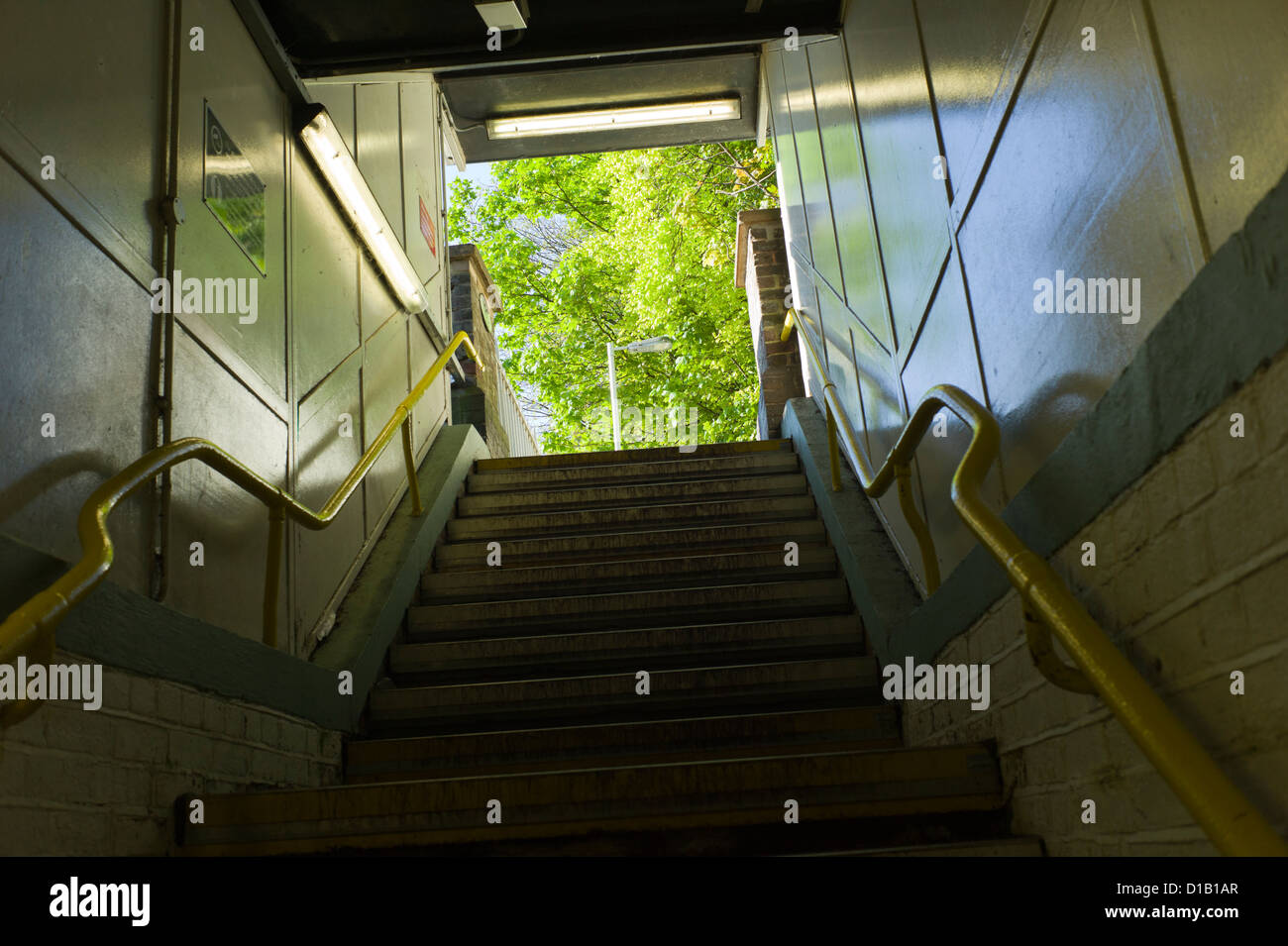 U-Bahn-Schritte auf der Suche nach oben, grüner Baum draußen, gelbes Geländer Stockfoto