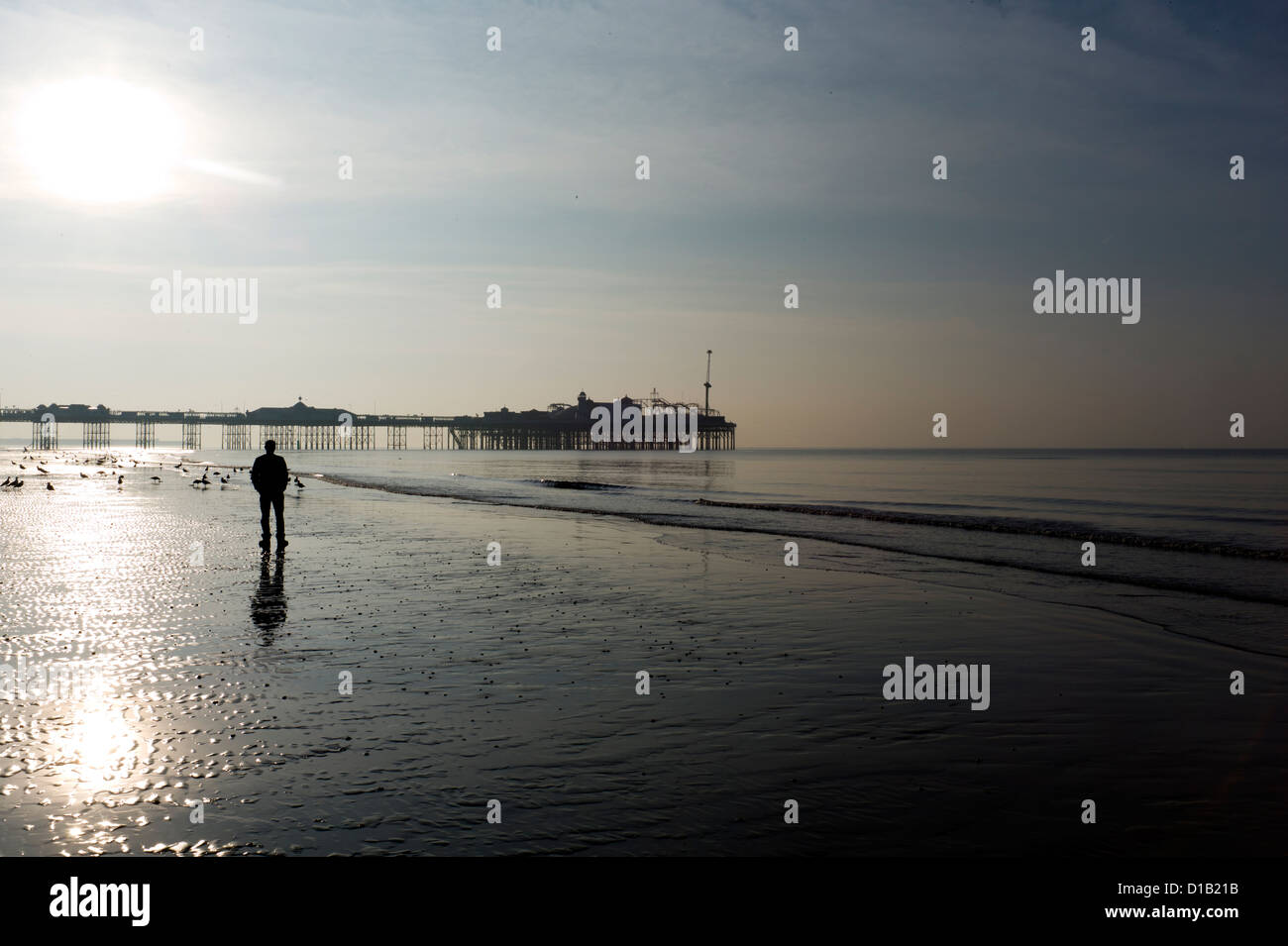 Einsame Figur spiegelt sich im nassen Sand, bei Ebbe, Morgen, Brighton Stockfoto