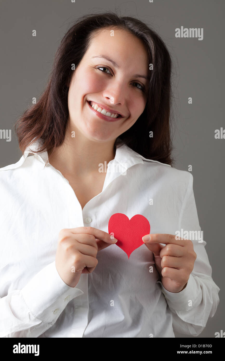 Lächelnde Frau hält ein rotes Herz Stockfoto