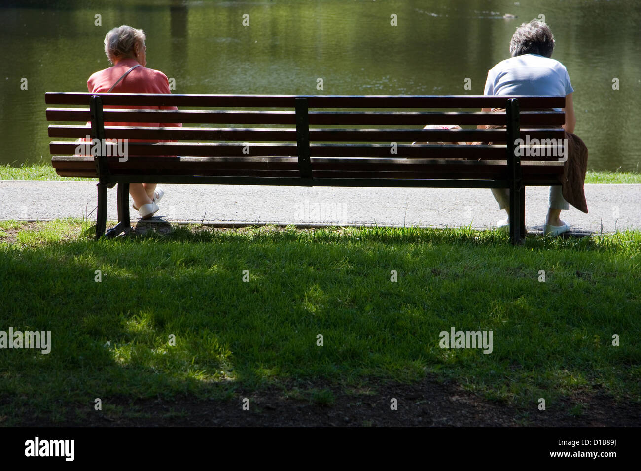 Berlin, Deutschland, zwei ältere Frauen separat auf einer Parkbank sitzen Stockfoto