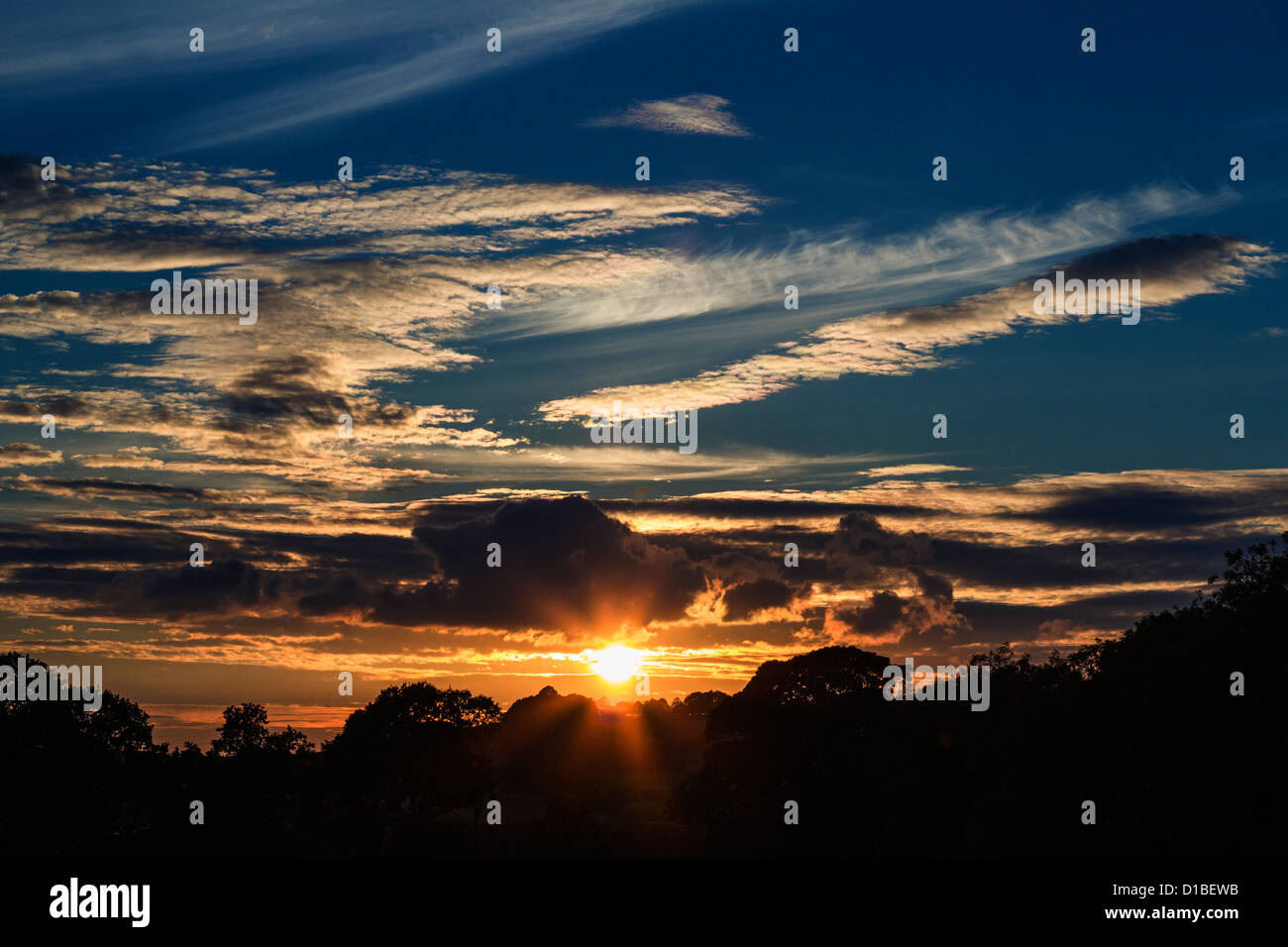 Sonnenuntergang mit vielen Wolken und Sonnenstrahlen. Eine kontrastreiche Mischung aus blau und Orange. Stockfoto