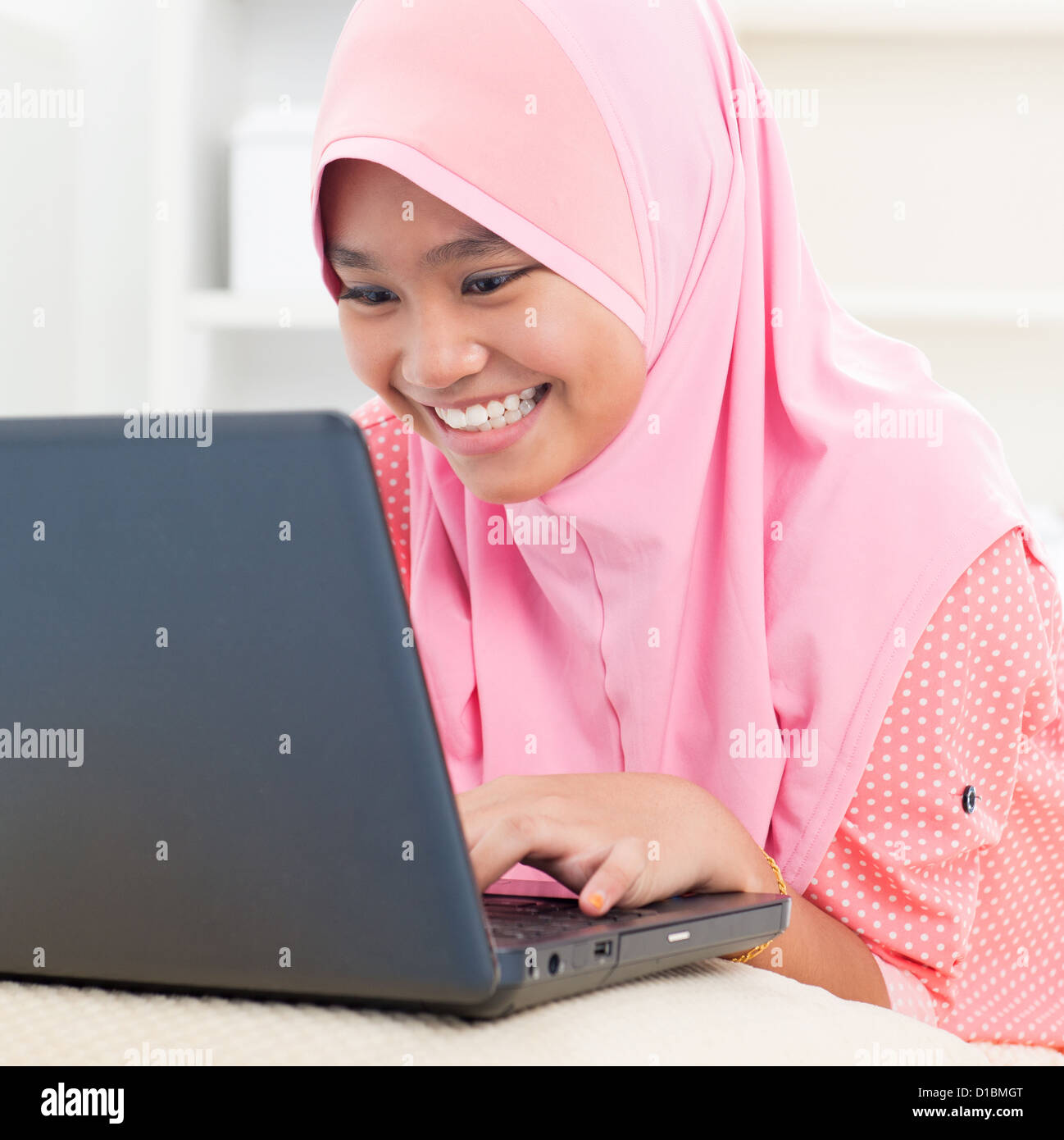 Asiatische Teenager mit Notebook zu Hause. Muslimische weibliche Teenager. Stockfoto