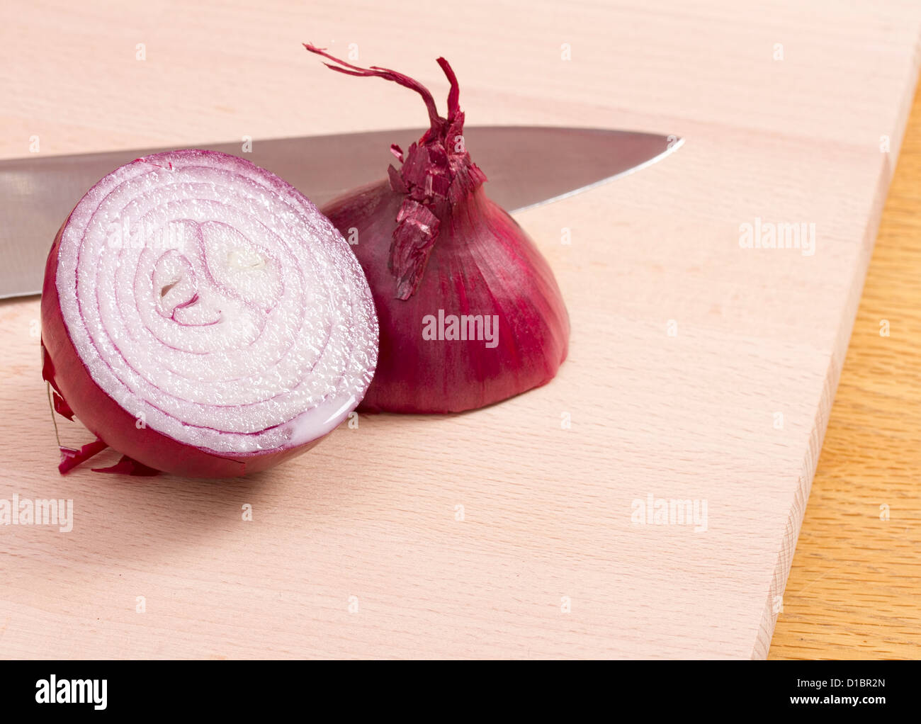 Rote Zwiebel-Hälften mit Messer auf Holzblock Stockfoto