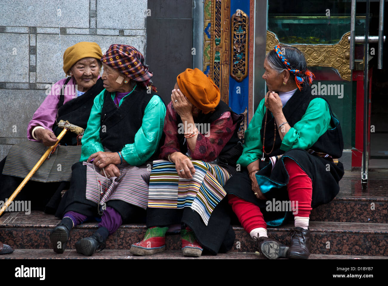 Vier ältere tibetische Frauen sitzen auf der Treppe entlang Barkhor Straße, alte Stadt Lhasa, Tibet Stockfoto