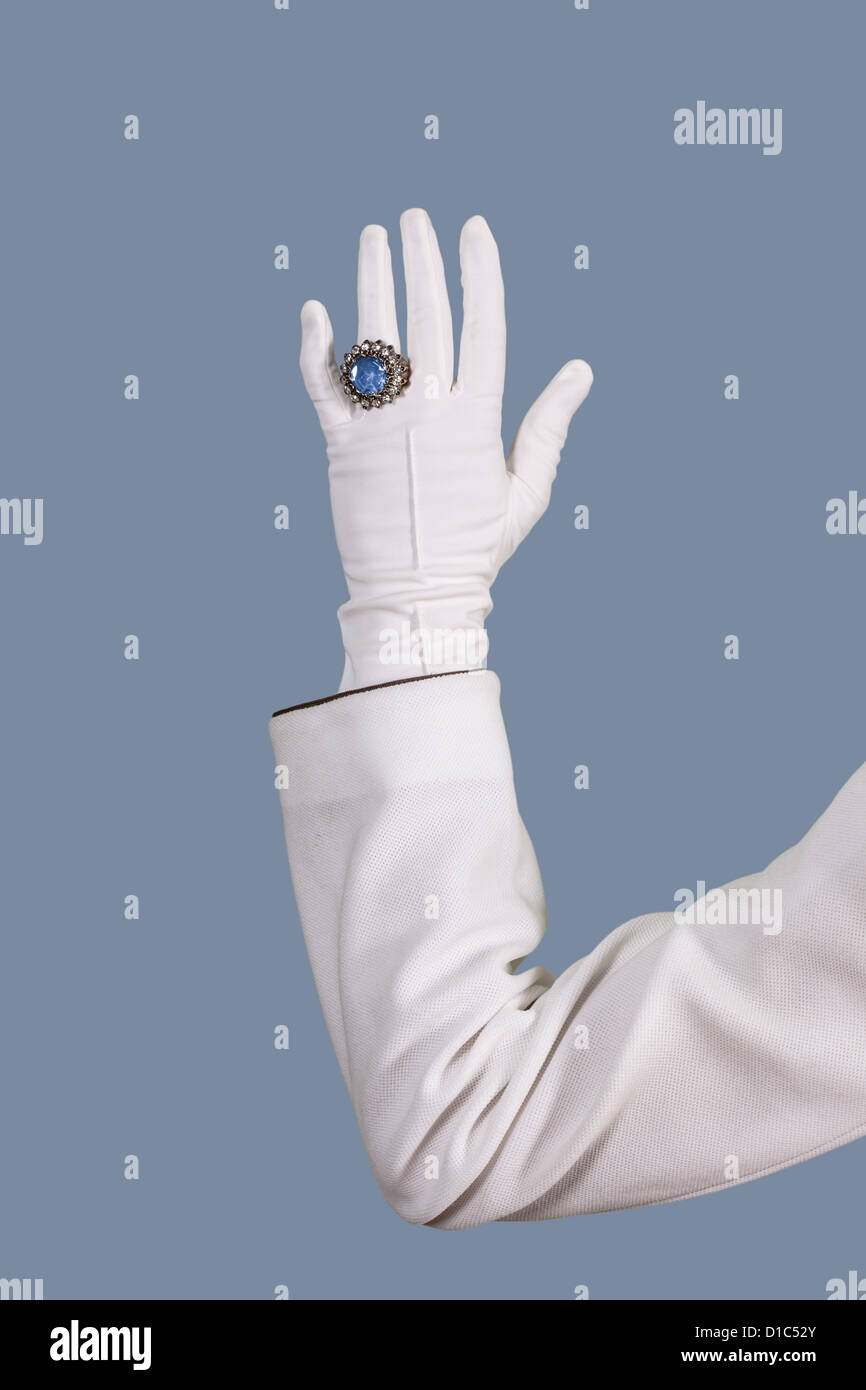 eine weibliche Hand in einem weißen Handschuh mit einem blauen ring Stockfoto