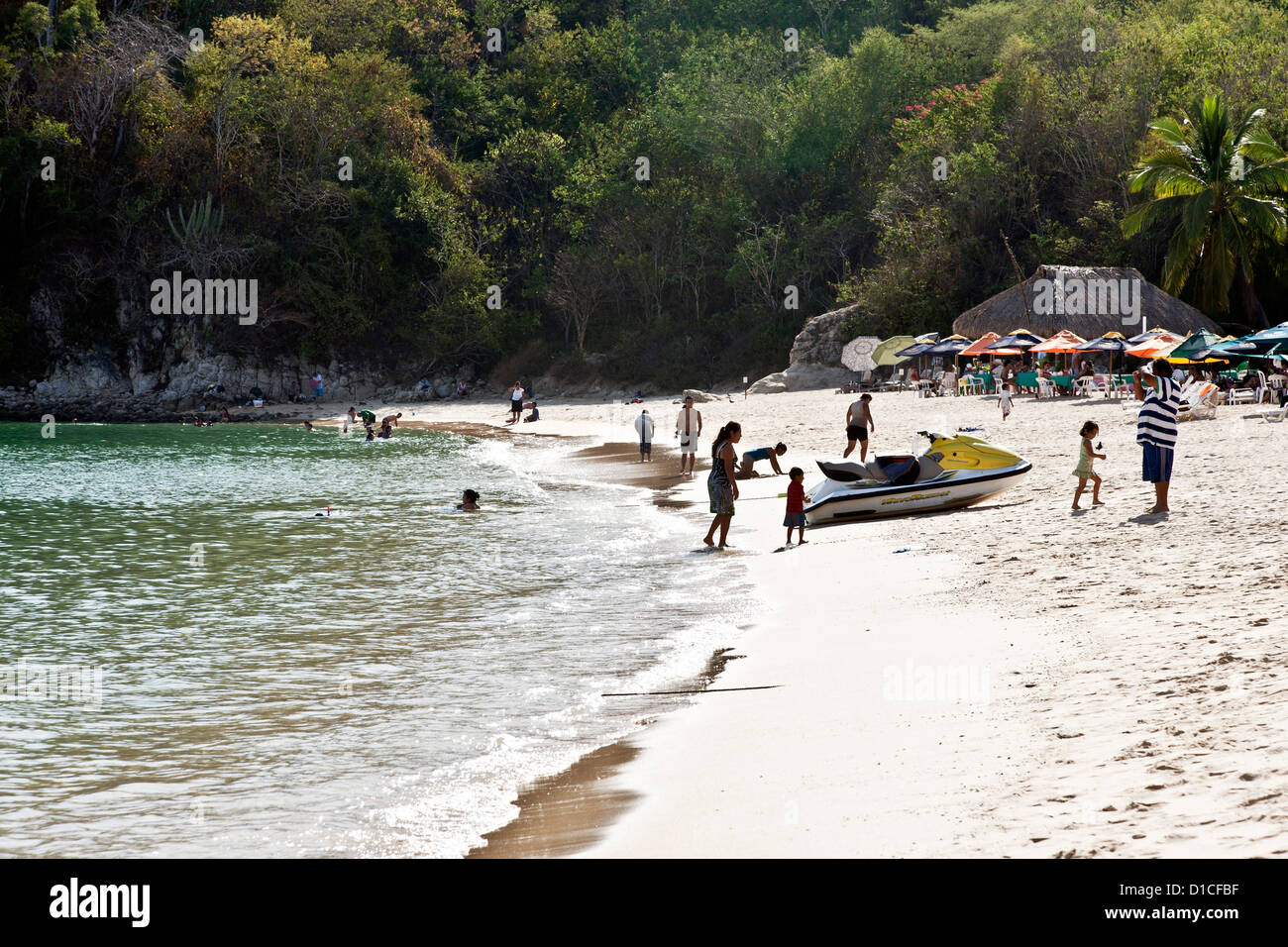 am Nachmittag leichte Silhouetten Menschen genießen Sandstrand & transluzent Wasser Dschungel Hintergrund von Playa Santa Cruz Stockfoto