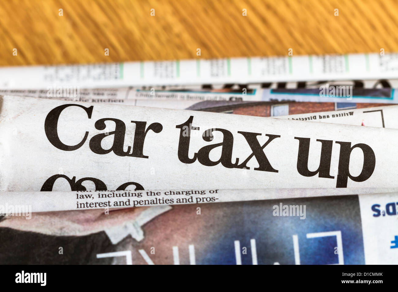 Zeitungen stapeln sich mit Schlagzeile über Kfz-Steuer in der Mitte des Bildes. Geringe Schärfentiefe. Stockfoto