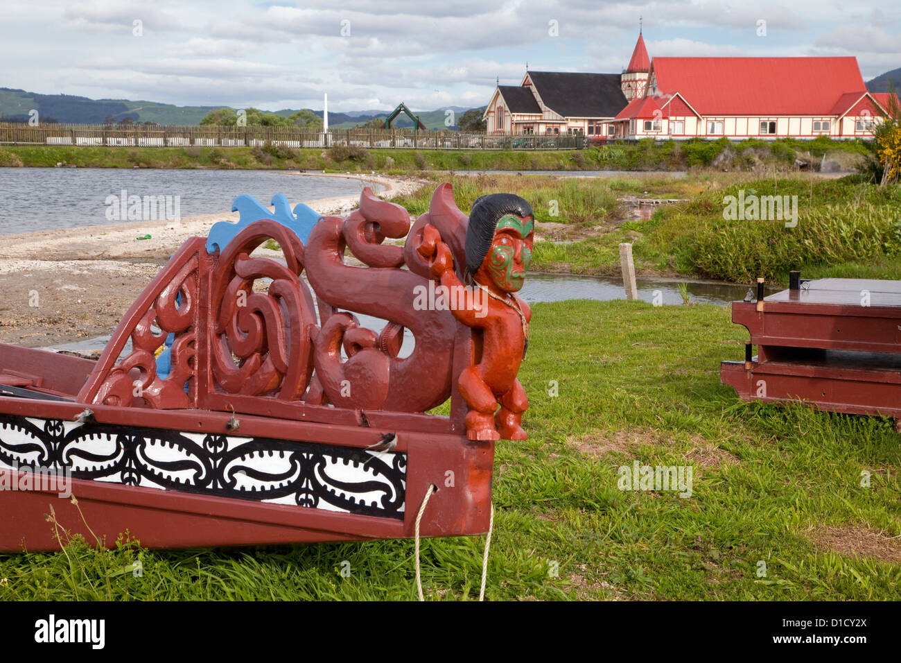 Dekoratives Detail am Heck der Maori Kanu, Ohinemutu Maori Dorf, Rotorua, Neuseeland. St. Faith Church im Hintergrund. Stockfoto