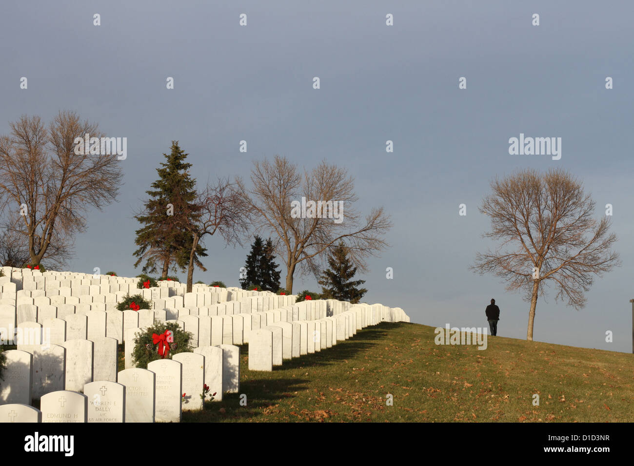 Ein Mann geht in der Nähe der Gräber bei Fort Snelling Friedhof zu Weihnachten. Stockfoto
