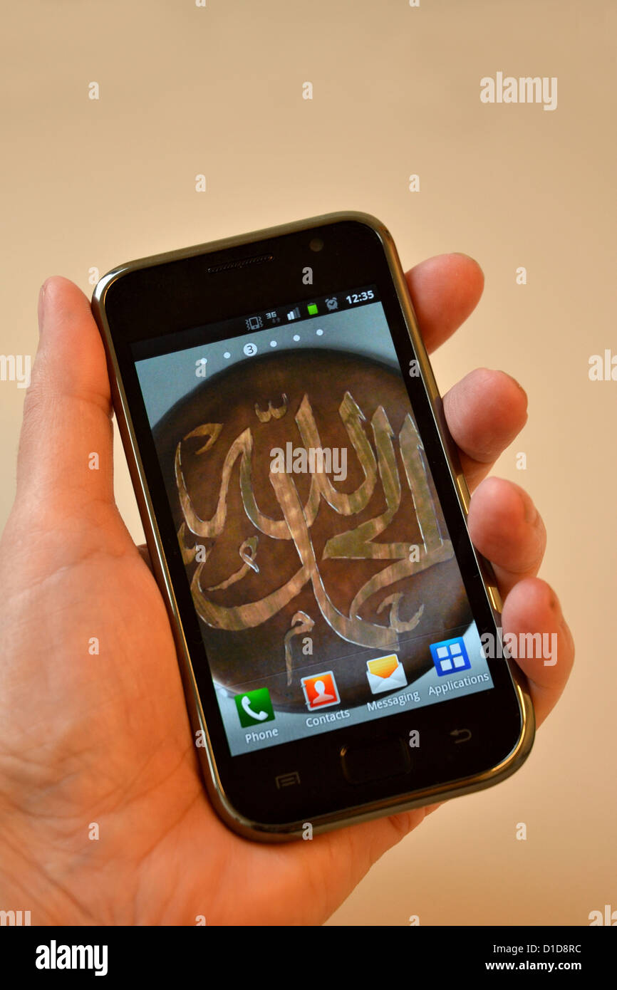 Islam im 21. Jahrhundert - Handy mit arabischer Kalligraphie als Hintergrundbild. Stockfoto