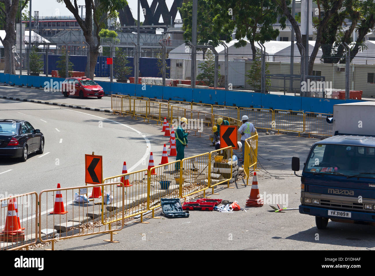 Arbeitnehmer mit Werkzeugen auf die Fahrbahn und an den Seiten, jährlich Vorbereitung für das Formel1 Rennen auf den Straßen von Singapur Stockfoto