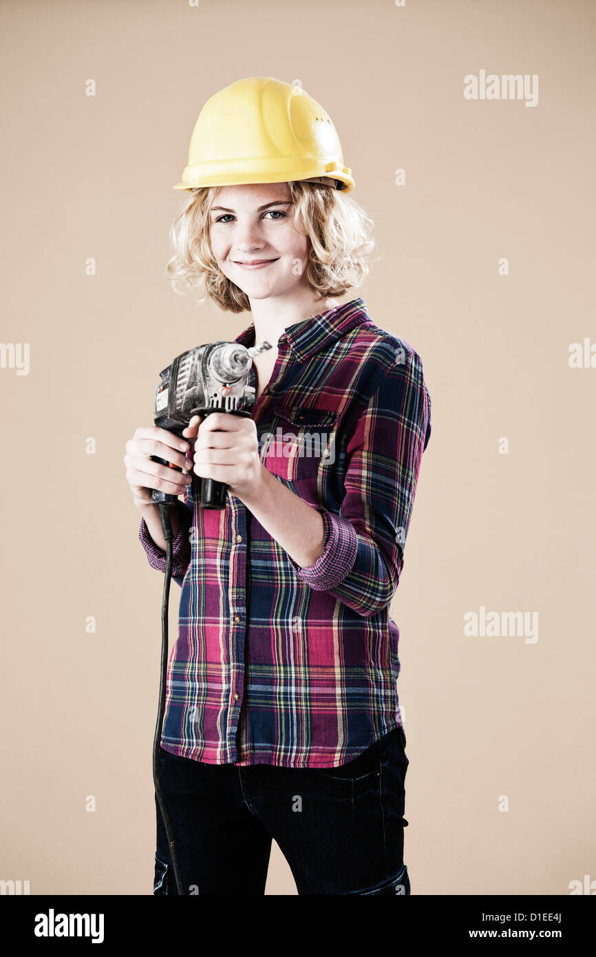 Teenager-Mädchen mit harten Helm und Bohrmaschine Stockfoto