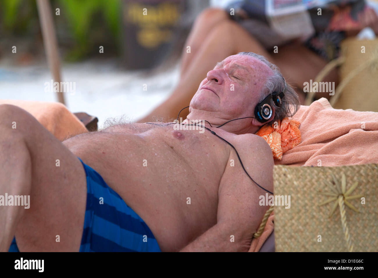 Älterer Mann tragen Kopf Handys Sonnenbaden am Chaweng Beach auf der Insel Ko Samui, Thailand. Stockfoto