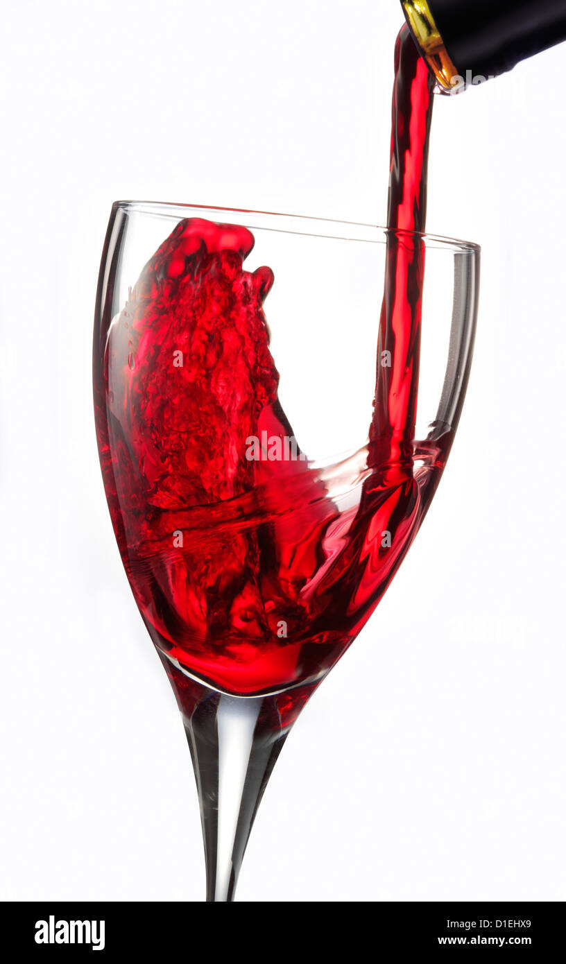 Stoppen Sie Action Stillleben Foto von Rotwein, der vor weißem Hintergrund in ein Glas gegossen wird Stockfoto