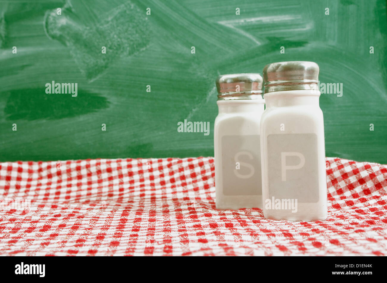 Salz- und Pfefferstreuer auf einem Küchentisch mit rot-weiß karierte Tischdecke. Stockfoto