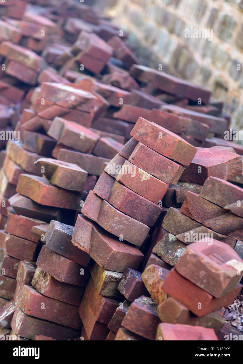 Alte handgemachte Ziegel in Haufen gestapelt gegen Steinmauer Stockfoto