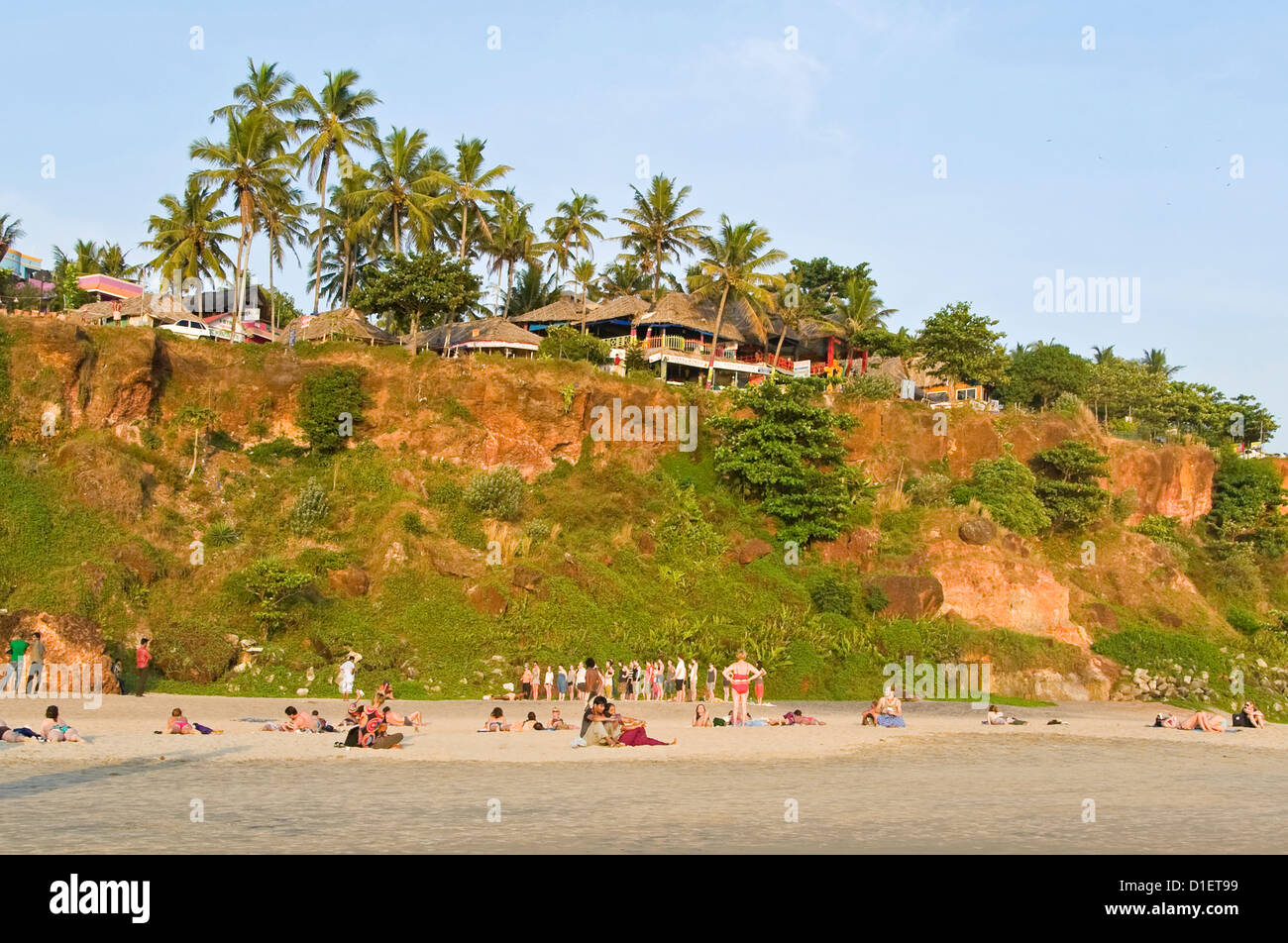 Horizontale Ansicht der Leute sitzen relaxen am Strand mit einem Yoga-Kurs im Hintergrund in Varkala, Kerala gehalten. Stockfoto