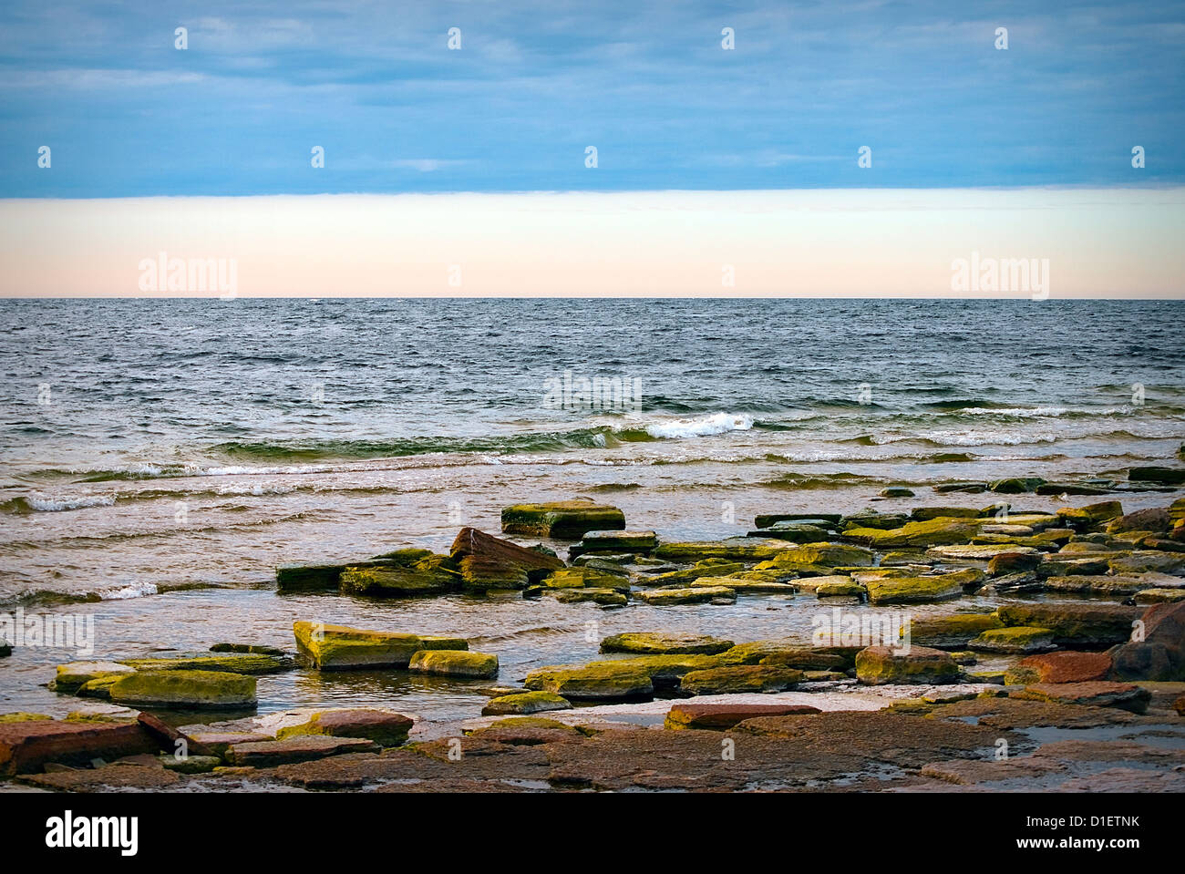 Bunten Steinen am Strand und einen herrlichen Himmel mit dunklen Wolken blau Stockfoto