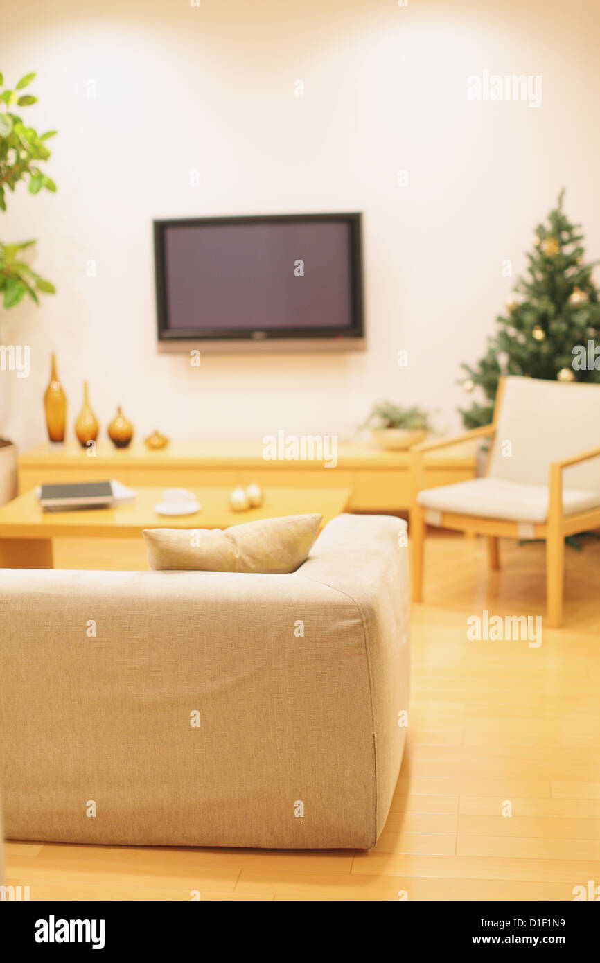 Wohnzimmer mit Möbeln, LCD-TV an der Wand und ein Weihnachtsbaum im Hintergrund Stockfoto