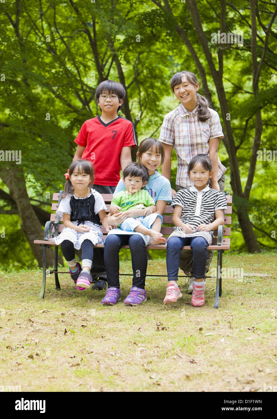 Geschwister in einer großen Familie auf einer Bank sitzend Stockfoto