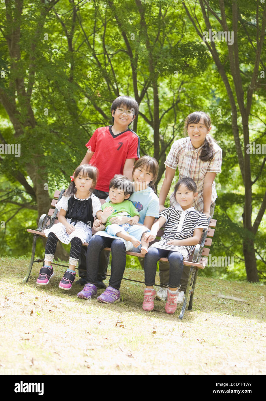 Geschwister in einer großen Familie auf einer Bank sitzend Stockfoto