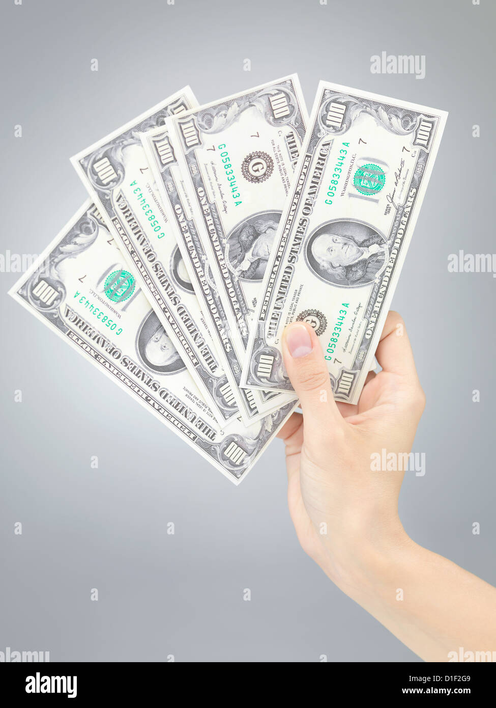 weibliche Hand, die hält hundert-Dollar-Scheine auf grauem Farbverlauf Hintergrund Stockfoto