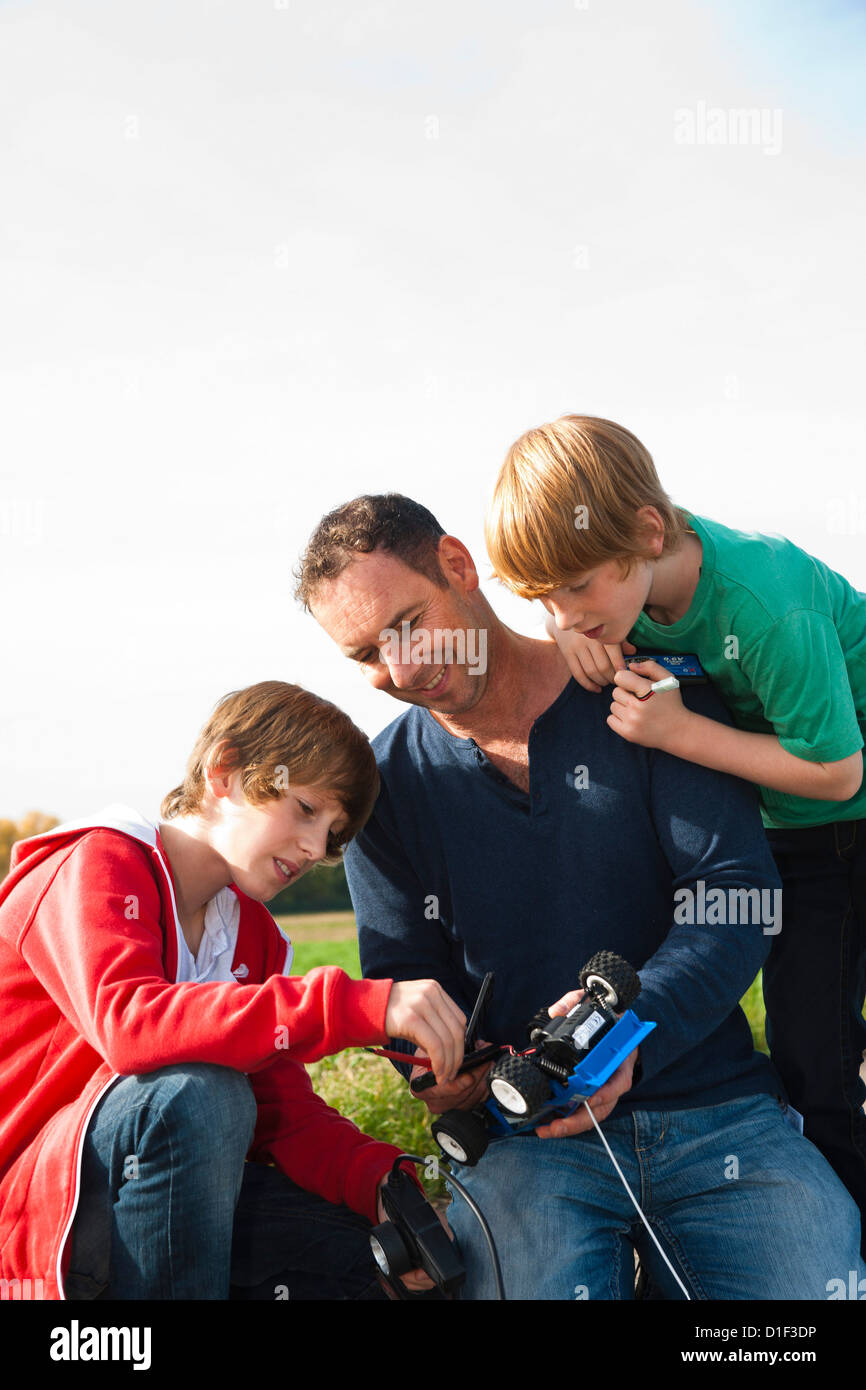 Vater mit seinen Söhnen am ferngesteuerten Spielzeugauto basteln Stockfoto