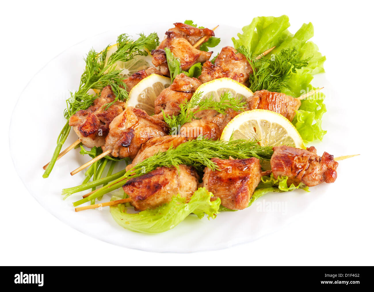 Grill-Hähnchen am Spieß mit Zitrone und Salatblätter auf Teller, isoliert auf weißem Hintergrund Stockfoto