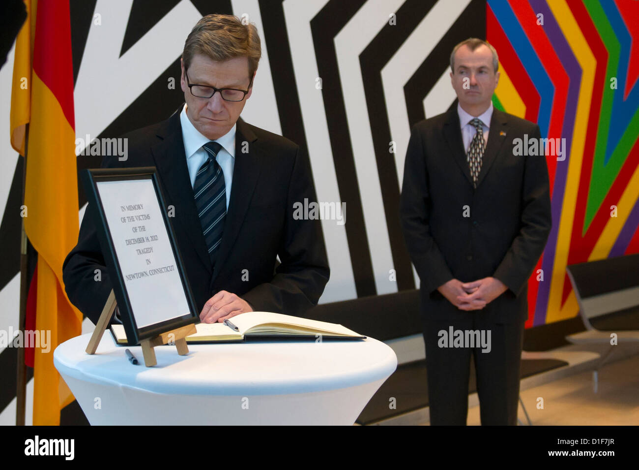 Bundesaußenminister Guido Westerwelle unterschreibt das Buch der Anteilnahme für die Opfer von den Amoklauf in den USA bei der amerikanischen Botschaft, während US-Botschafter Philip Murphy hinter ihm in Berlin, Deutschland, 18. Dezember 2012 steht. 26 Personen und der Schütze starb bei einem Amoklauf an einer Grundschule in Newtown, Connecticut in den USA. Foto: MARC TIRL Stockfoto
