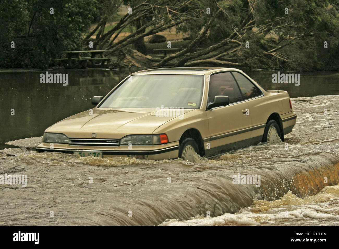 Autofahrer im Auto fahren durch tiefe und gefährlich schnell fließenden Fluten dem Fluss kreuzt einer Straße in Australien Stockfoto