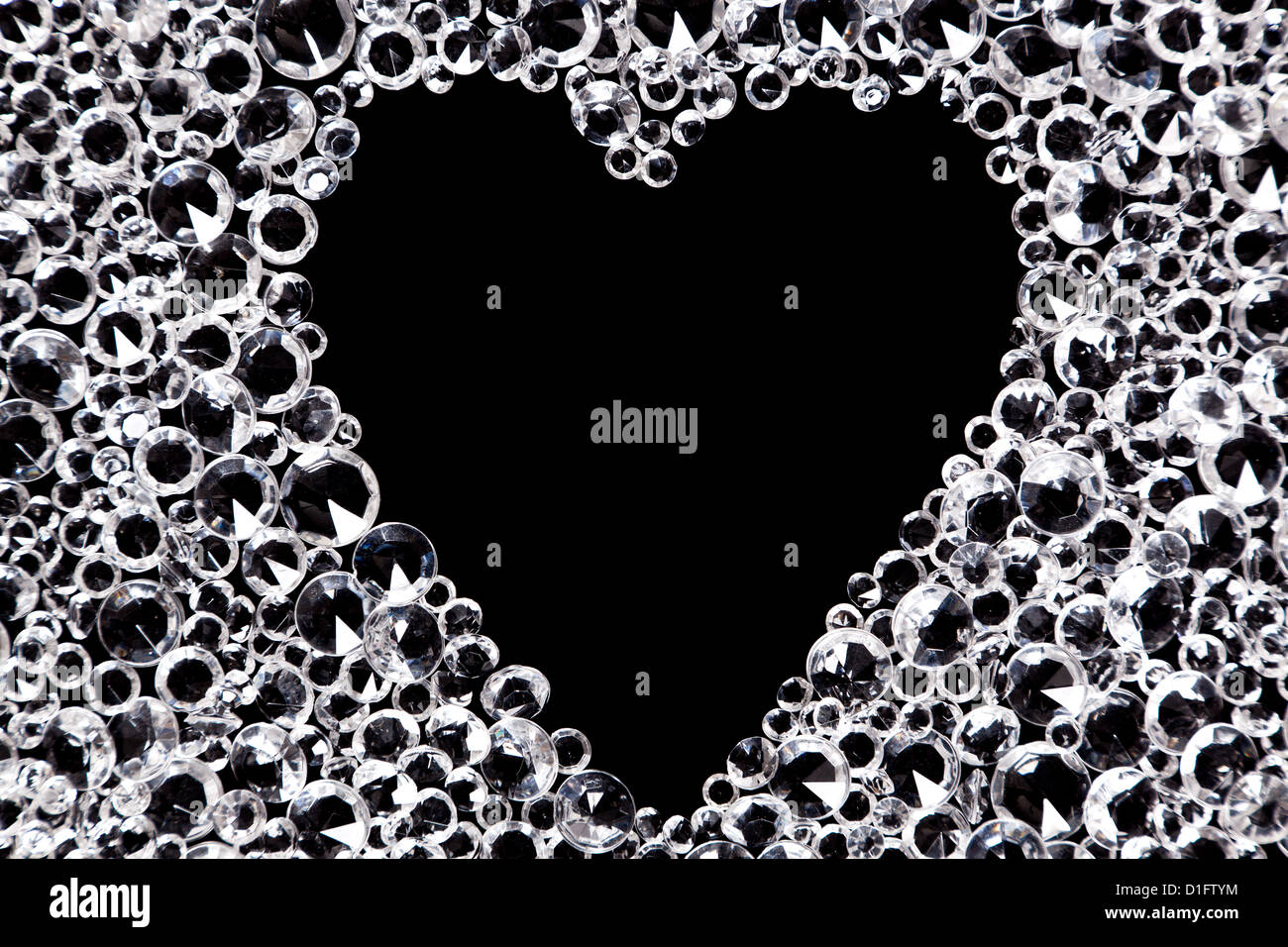 Hunderte von Nachahmung Diamanten auf einem schwarzen Hintergrund mit einem herzförmigen Raum in der Mitte. Stockfoto
