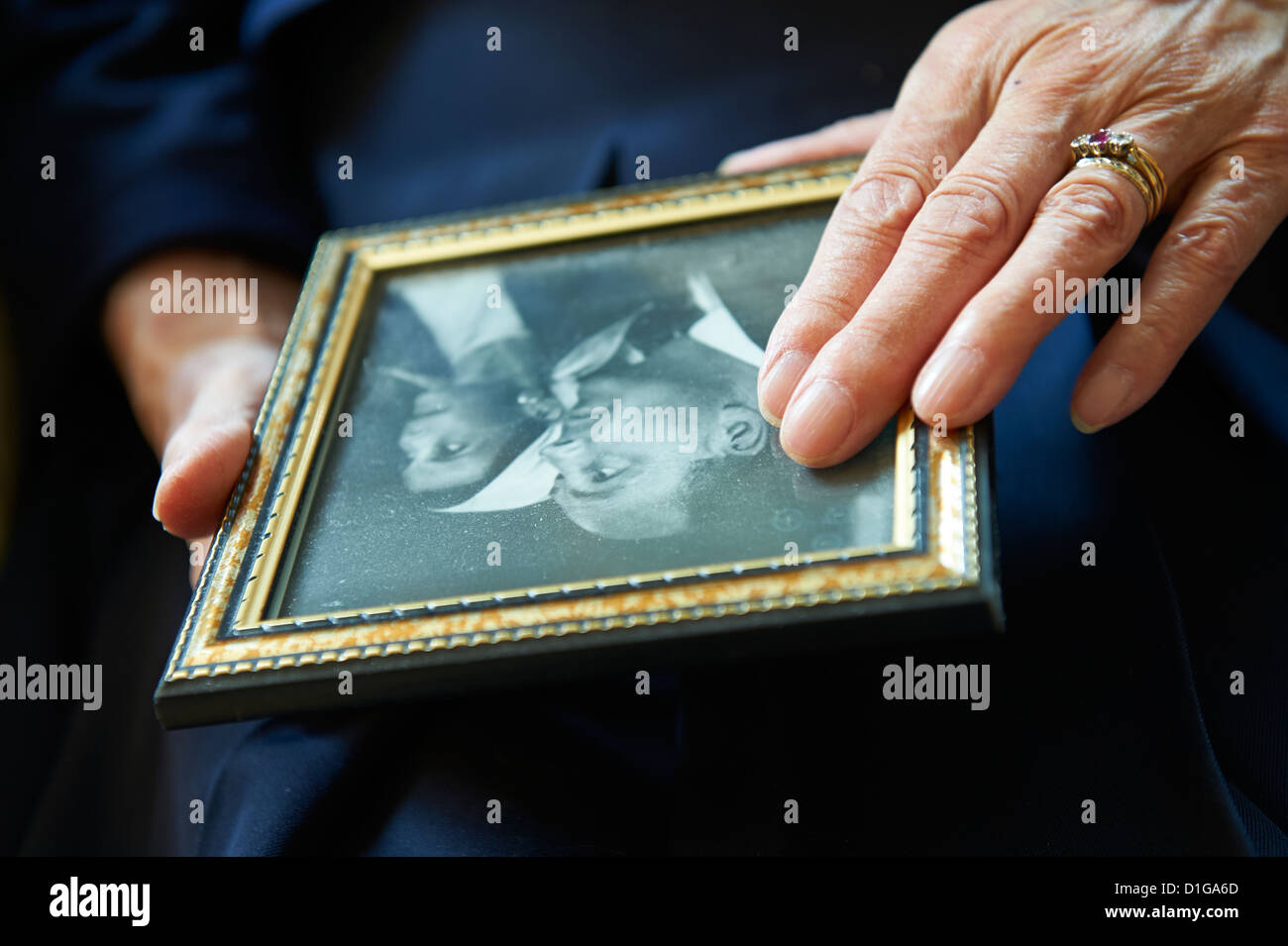 Senior zu Hause halten alte Hochzeitsfoto von sich selbst und verstorbenen Mann Stockfoto