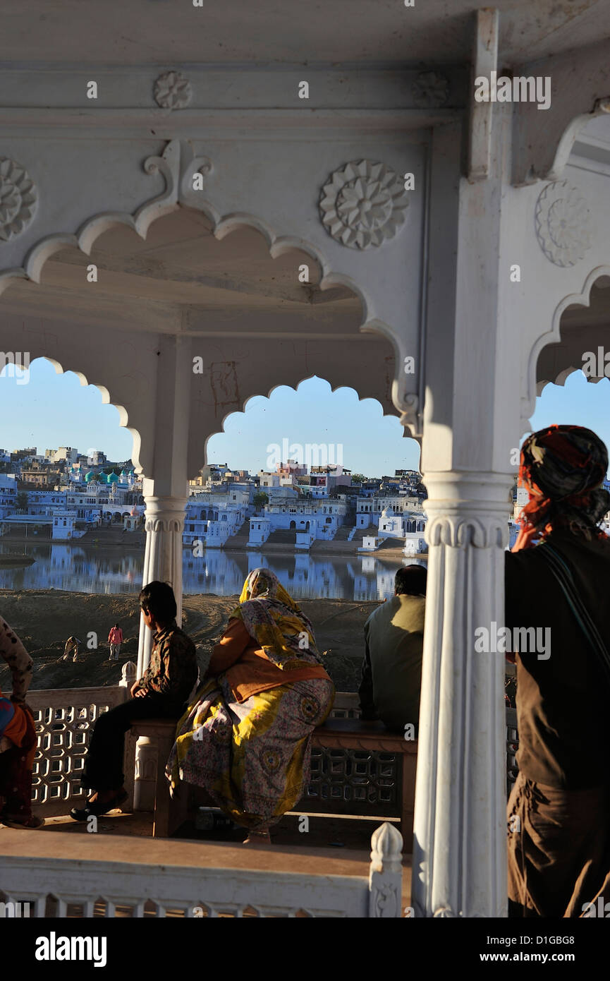 Einige indische Pilger sowie ein Westler betrachten die genial Ghat und den See in Pushkar; Rajasthan, Indien. Stockfoto